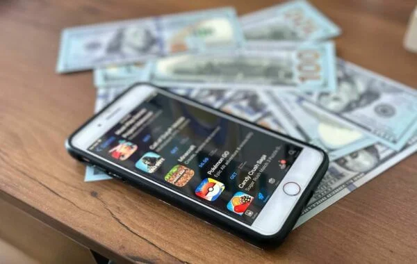 A phone with mobile gaming apps and cash on a table